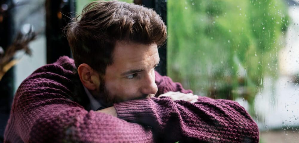 Muž pozerá von oknom